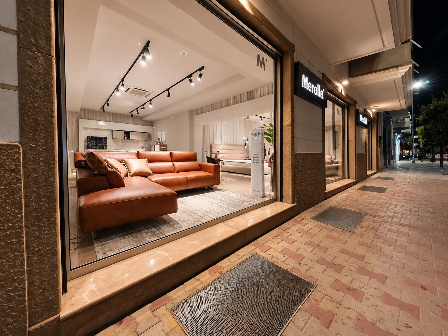 L’ingresso dello showroom Merolla in Via Ragni la sera, con le vetrine illuminate e un divano in pelle esposto